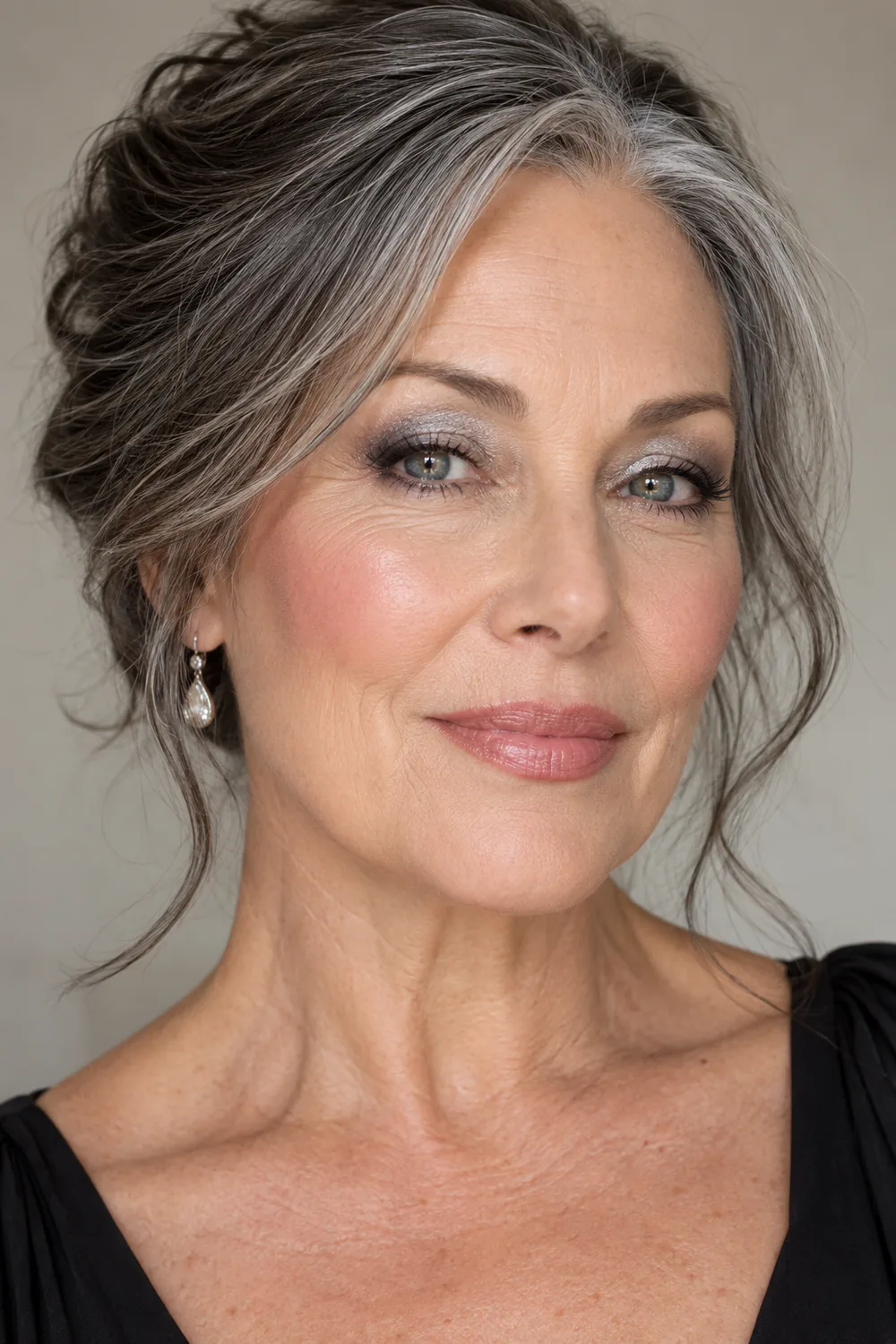 Mature woman with silver-to-graphite smoky eyeshadow, softly blurred black liner, cool rose blush, and muted beige-pink lipstick.