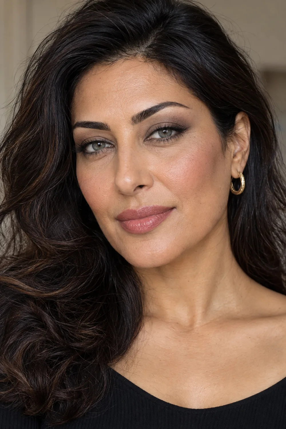 Adult woman with olive-tan skin, open hooded gray-green eyes, soft gray-brown shadow, diffused charcoal outer corners, mauve blush, and neutral rose lipstick.