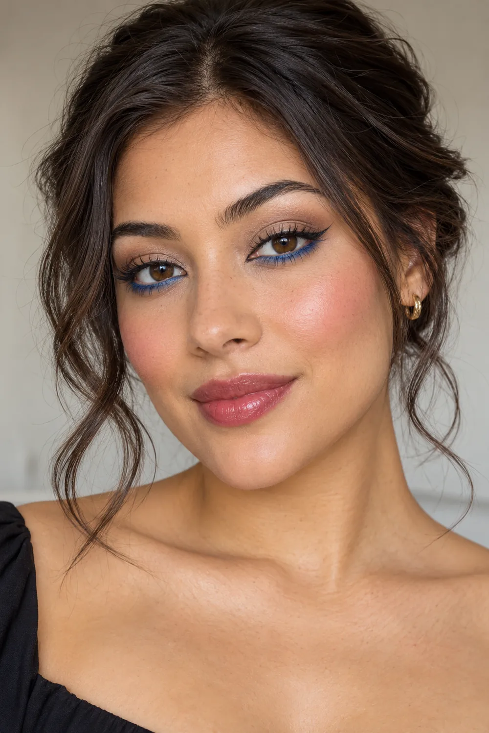 Adult woman with cobalt lower-lash liner, taupe lids, short brown flick, soft flush, and sheer berry lips.