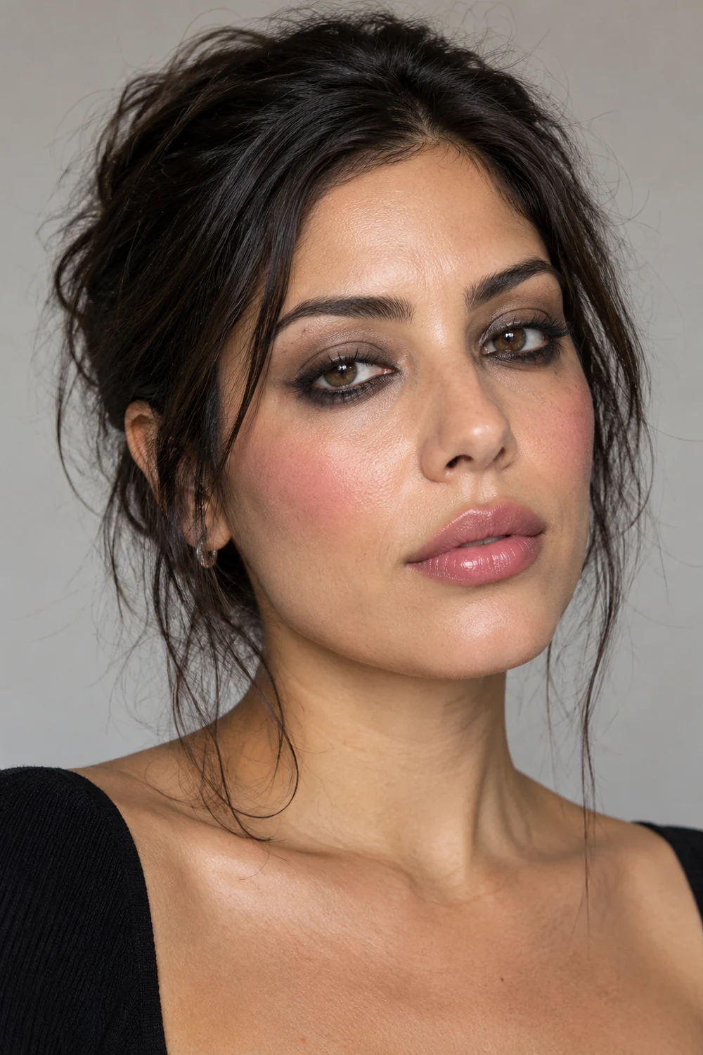 Close portrait of an adult woman with dark brown eyes, smudged charcoal eyeliner, taupe crease shadow, rose blush, and sheer pink lips.