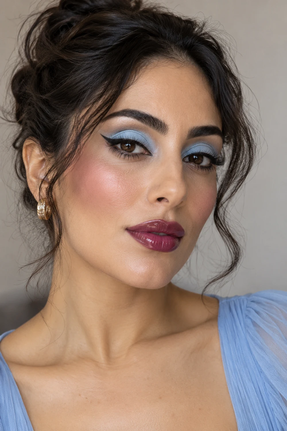 Adult woman with matte powder-blue eyeshadow, crisp black winged liner, softly blended plum blush, and glossy berry lips.