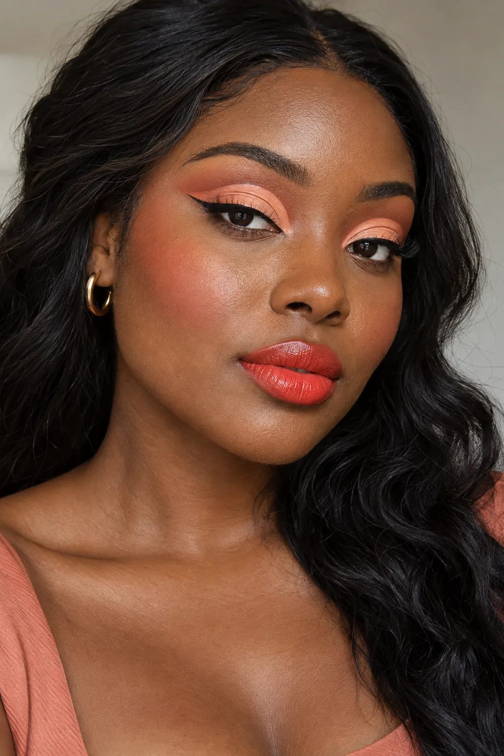 Fictional adult Black woman with pale peach lids, coral-peach cut crease, toasted peach shading, thin straight-out black liner, softly blended lower cheek blush, and vivid coral-red satin lips.