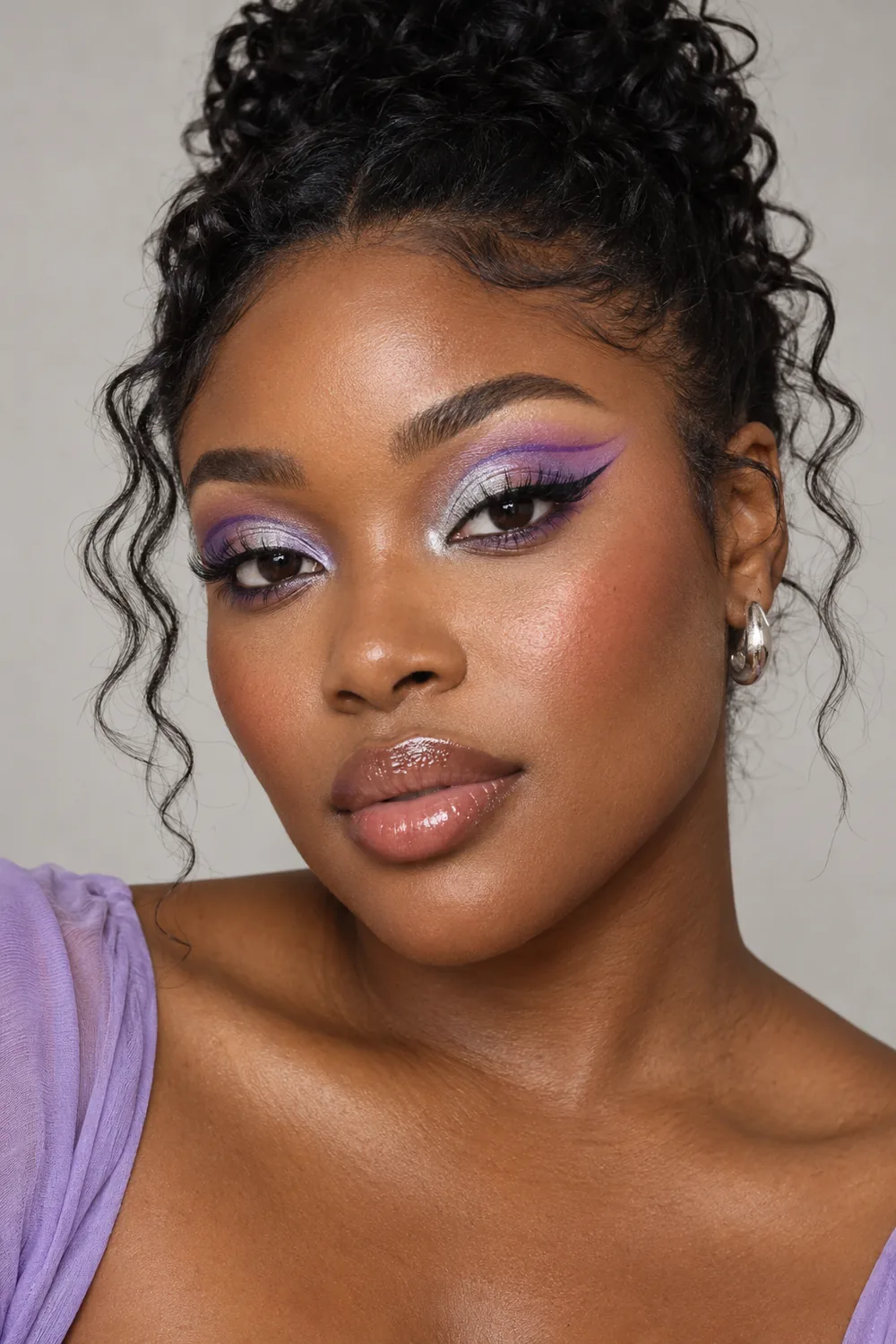 Fictional adult Black woman with silver inner-lid shimmer, lilac outer-lid shadow, a violet double wing, peach blush, and glossy lips.